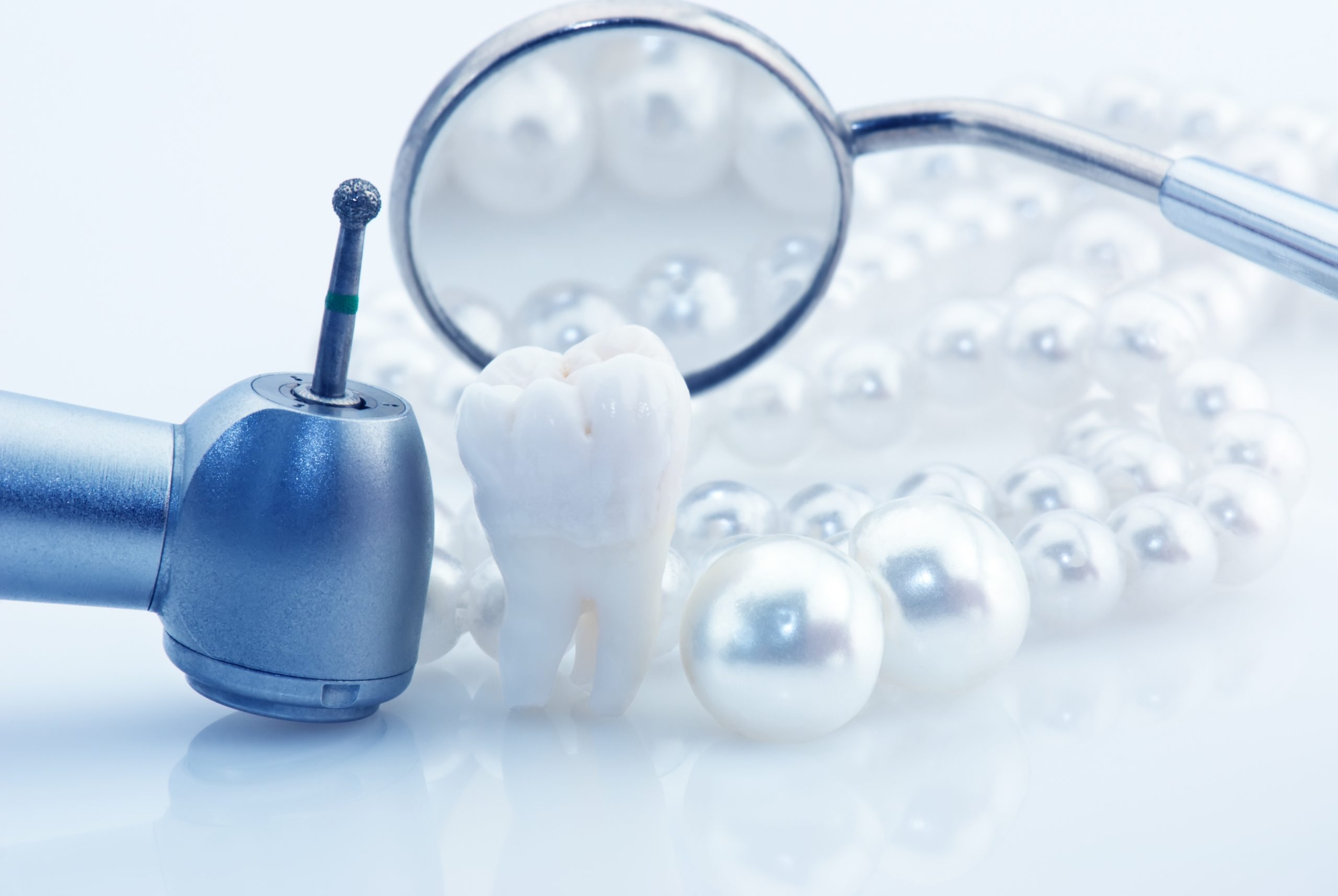 Healthy teeth concept. Real human wisdom tooth natural pearls dental mirror and drill. Blue tinted image